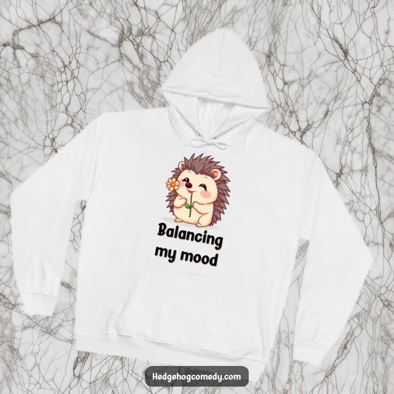 Funny Kawaii Hedgehog Hoodie: A cute hedgehog attempts a delicate balance, with a small flower wobbling on its nose.