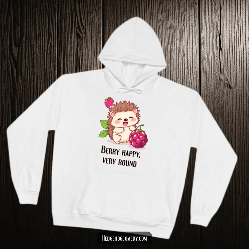 Funny hoodie graphic depicting a cute hedgehog enthusiastically rolling a giant berry, conveying humorous joy and contentment.